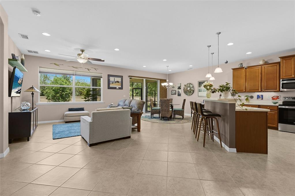 An open-concept living room, dining area, and kitchen with tile floors and neutral walls — 6240 FALCON LAIR DRIVE, NORTH PORT, FL