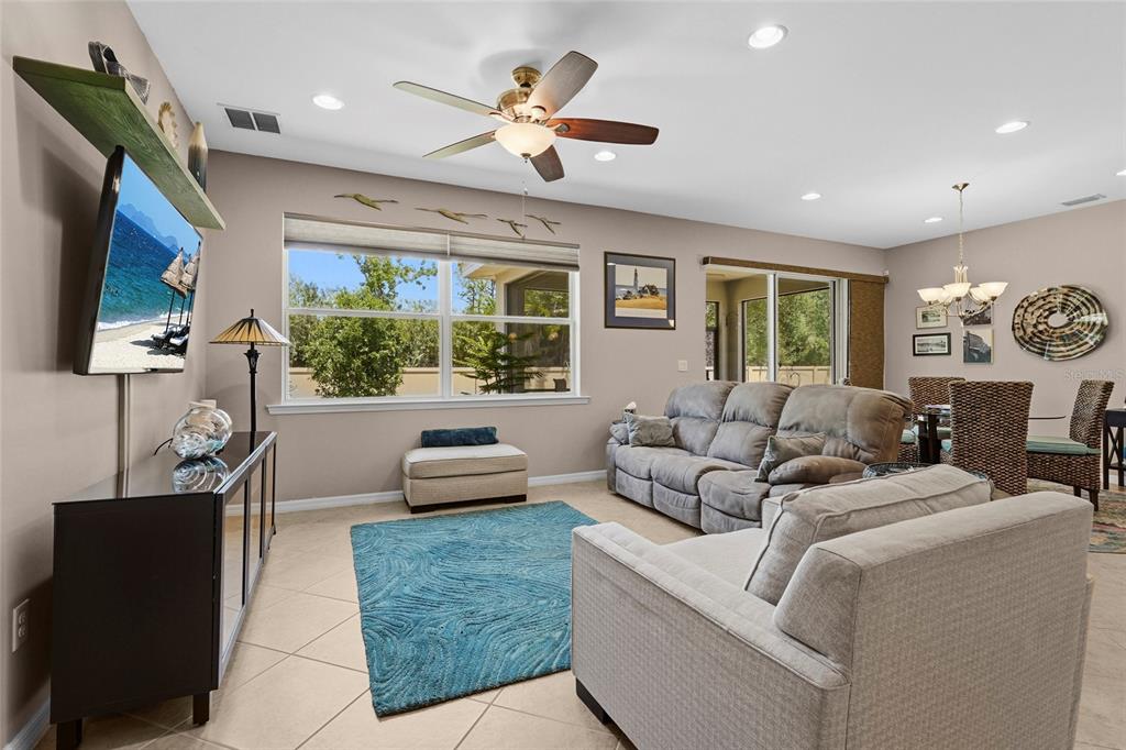 A living room with a ceiling fan, a blue area rug, and a television console — 6240 FALCON LAIR DRIVE, NORTH PORT, FL