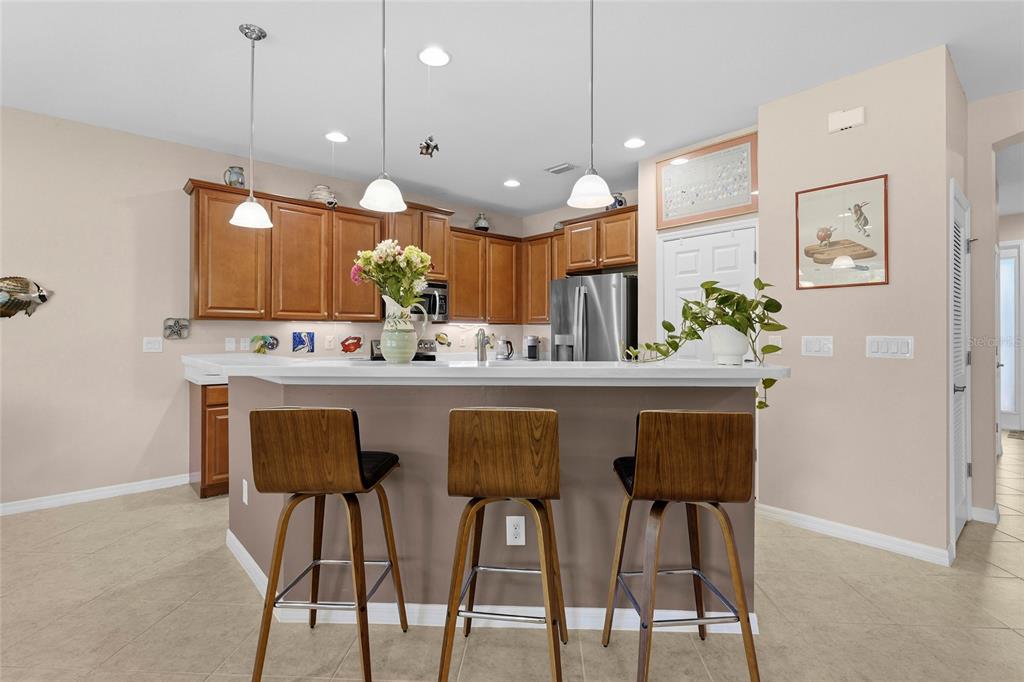 A kitchen features wood cabinets, a breakfast bar with three stools, and pendant lighting — 6240 FALCON LAIR DRIVE, NORTH PORT, FL