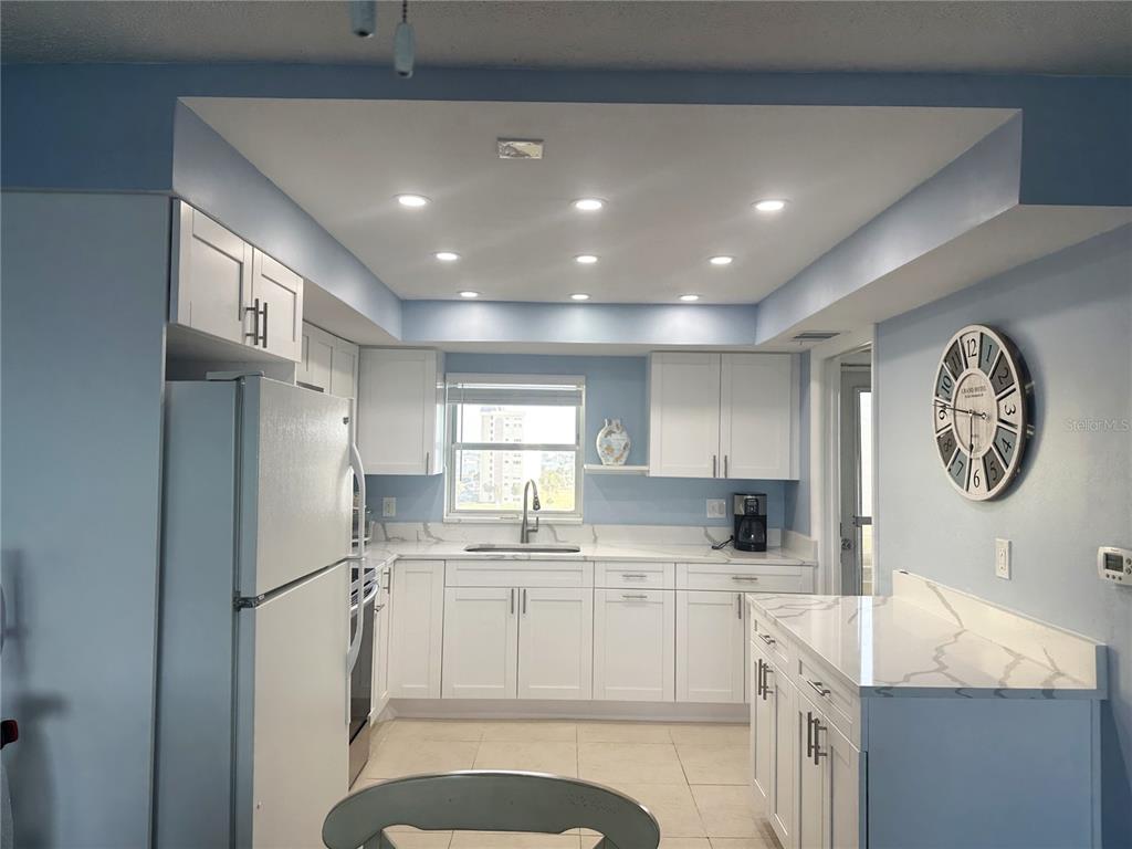 A kitchen features white cabinets, light countertops, a window above the sink, and recessed lighting — 4725 COVE CIRCLE UNIT 804, ST PETERSBURG, FL