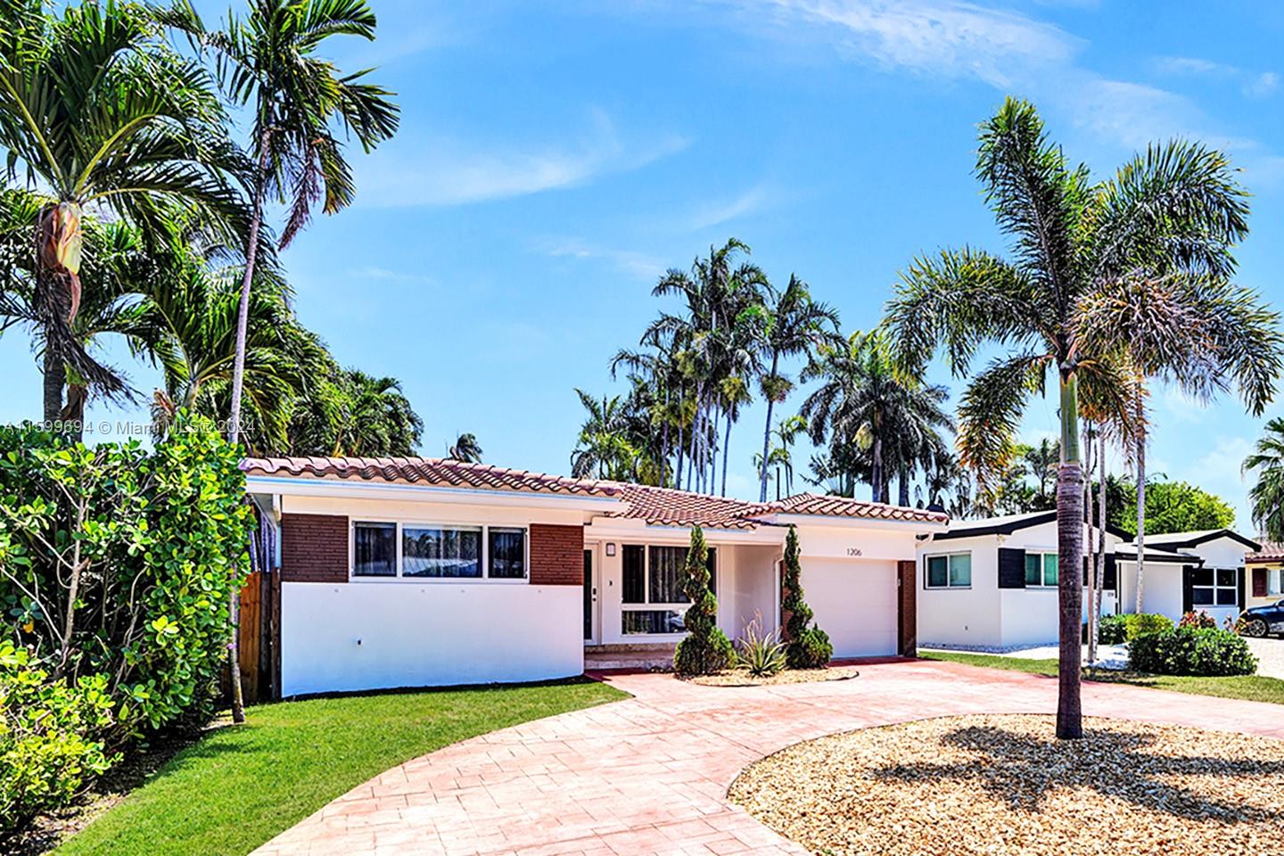 A single-story house with a white facade, brown brick accents, and a paved driveway — 1206 Lincoln St, Hollywood FL 33019, HOLLYWOOD, FL