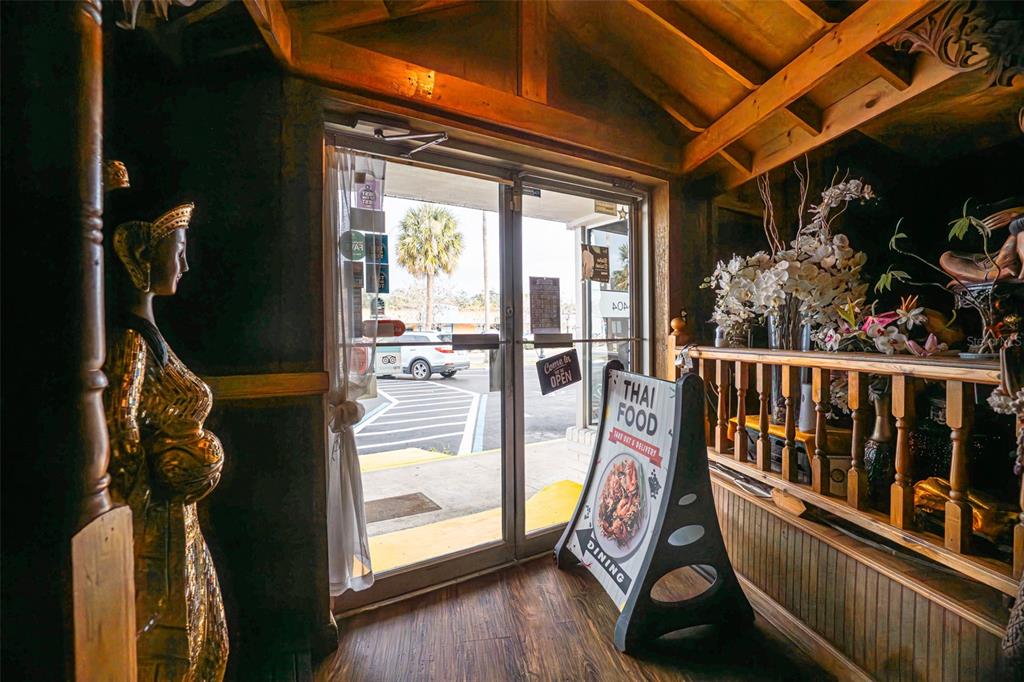 The entrance of a Thai restaurant features a decorative statue, wooden beams, and signage — 5414 MAIN STREET, NEW PORT RICHEY, FL