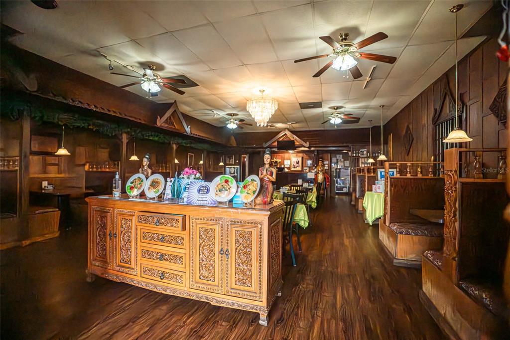 A restaurant interior features wooden paneling, carved furniture, ceiling fans, and traditional Thai-style decor — 5414 MAIN STREET, NEW PORT RICHEY, FL