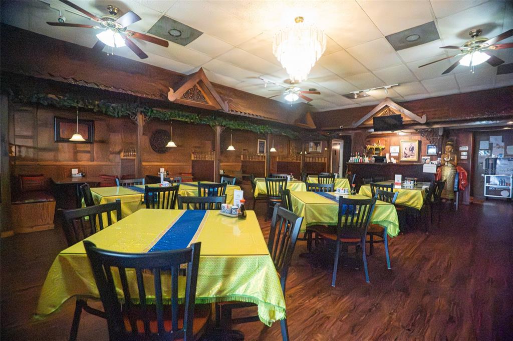 A restaurant dining room features yellow tablecloths, wooden walls, ceiling fans, and a central chandelier — 5414 MAIN STREET, NEW PORT RICHEY, FL