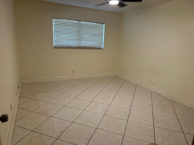 An empty bedroom features light-colored tile flooring, off-white walls, and a window with blinds — 6505 WINFIELD Boulevard # 14, Margate FL 33063, MARGATE, FL