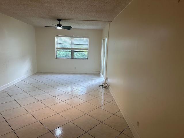 An empty room features light-colored tile flooring, a ceiling fan, and a large window — 6505 WINFIELD Boulevard # 14, Margate FL 33063, MARGATE, FL