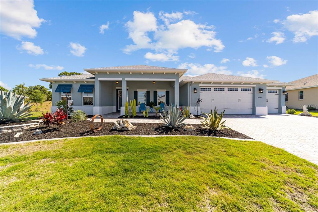 A single-story house with a gray exterior, a paved driveway, and desert-style landscaping — 10298 SW 96TH LOOP, OCALA, FL