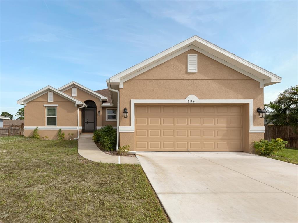 A single-story tan stucco house with a two-car garage and a concrete driveway — 886 EUCLID ROAD, VENICE, FL
