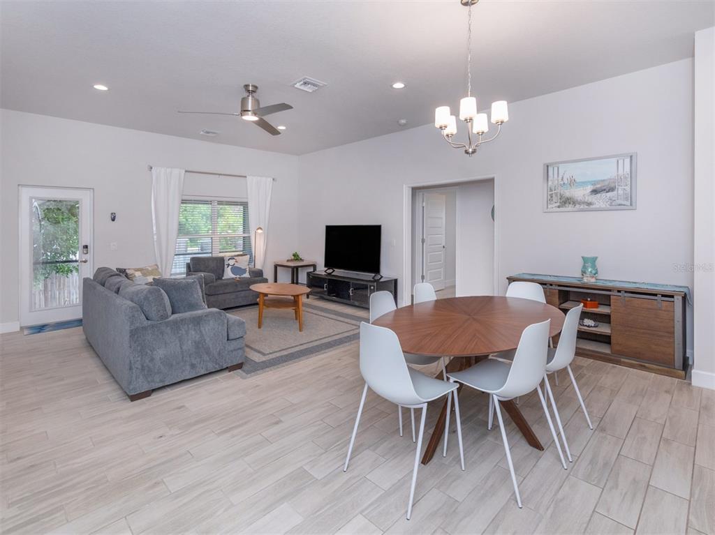 A living and dining room with light wood-look tile flooring, gray furniture, and white walls — 886 EUCLID ROAD, VENICE, FL