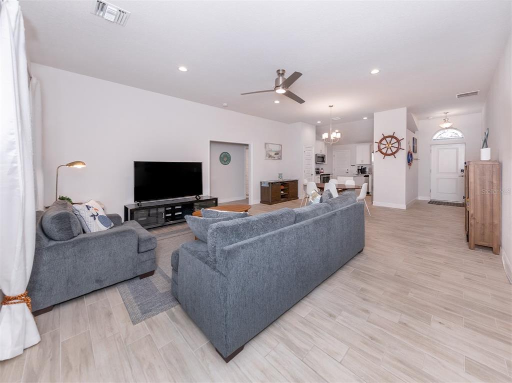 A living room with gray furniture, a television, and light-colored tile flooring — 886 EUCLID ROAD, VENICE, FL