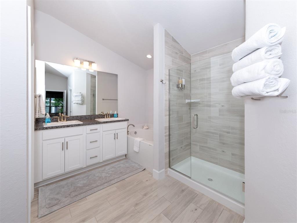 A bathroom features a double vanity, a glass-enclosed shower, and a soaking tub — 886 EUCLID ROAD, VENICE, FL