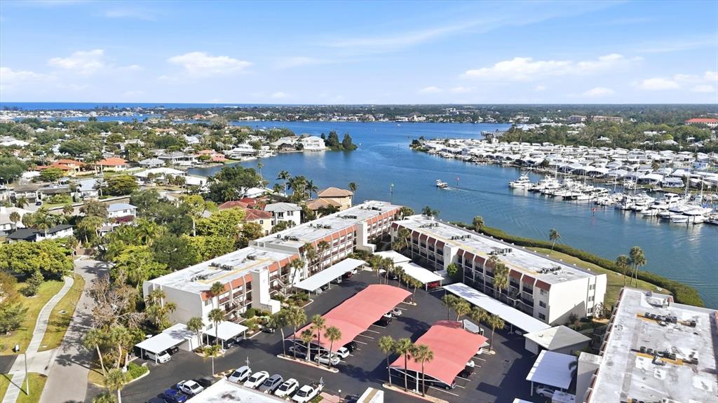 An aerial view shows a multi-story apartment complex with covered parking lots near a waterway — 260 SANTA MARIA STREET UNIT 105, VENICE, FL