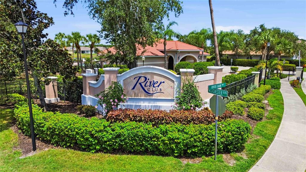 A community entrance sign for River Club stands before a building with a tiled roof — 4219 MANATEE LANE, PUNTA GORDA, FL