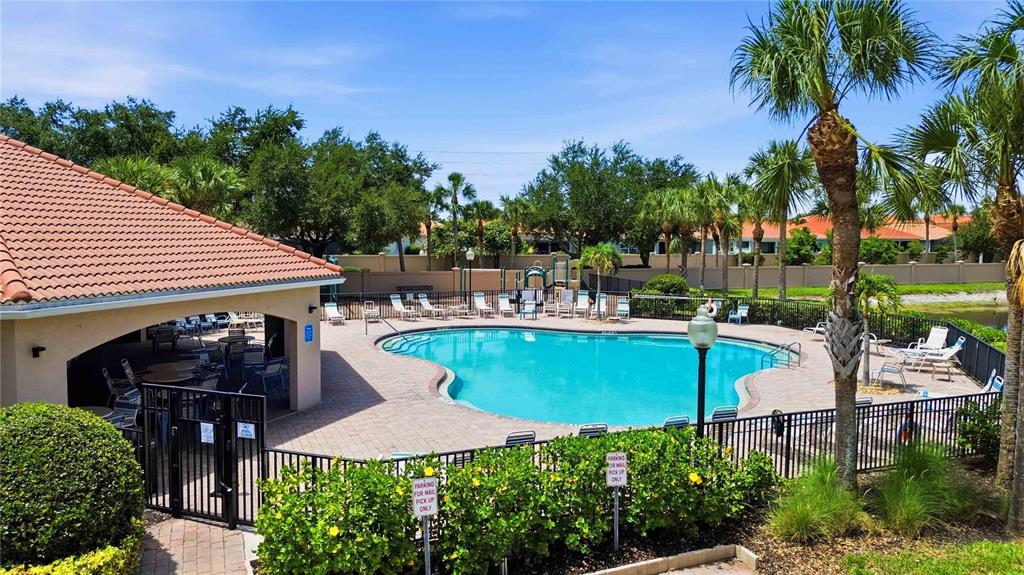 A swimming pool with a covered patio area and palm trees under a blue sky — 4219 MANATEE LANE, PUNTA GORDA, FL