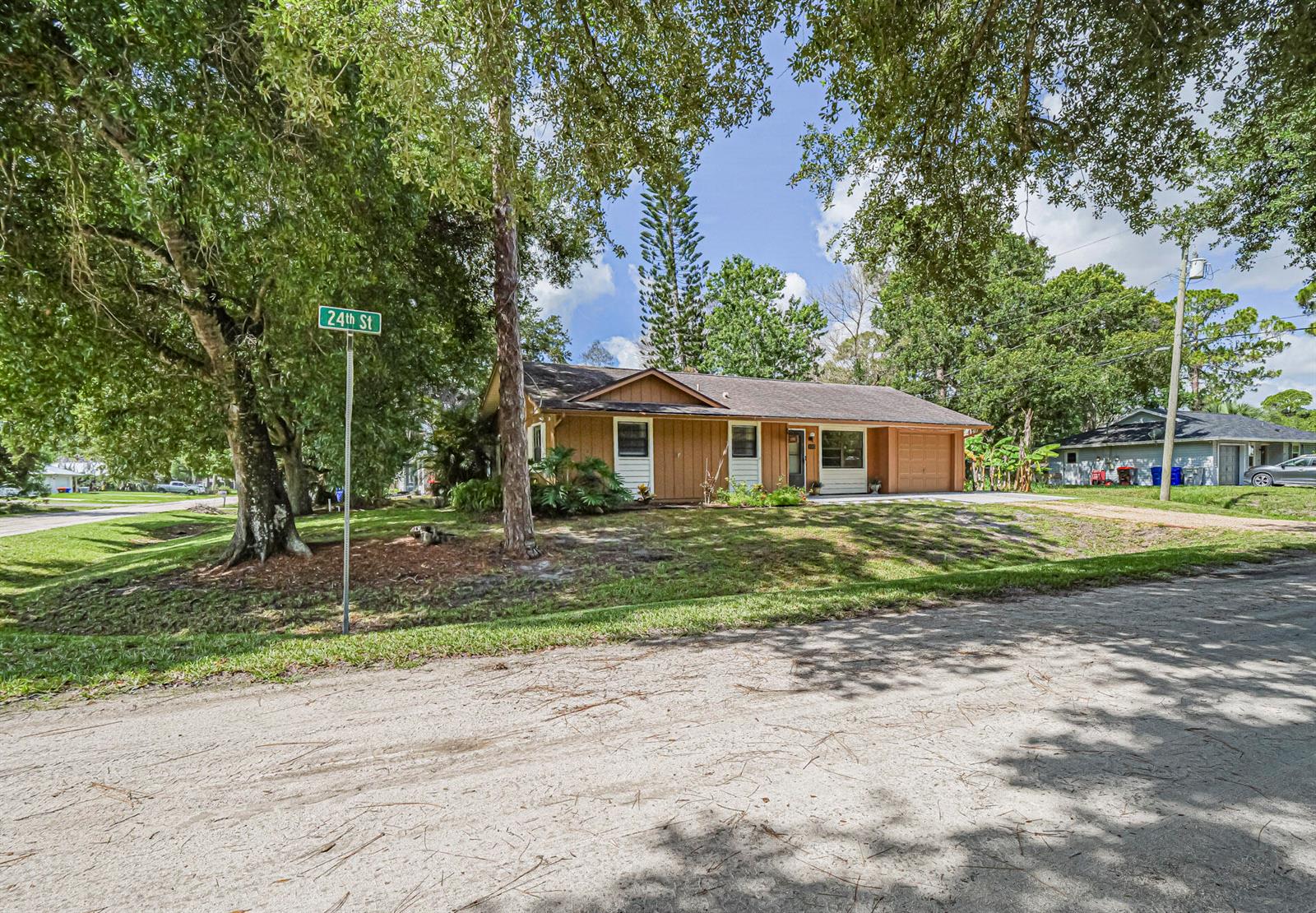 A single-story house with brown vertical siding and a garage sits on a grassy lot — 8745 24th Street, Vero Beach FL 32966, VERO BEACH, FL