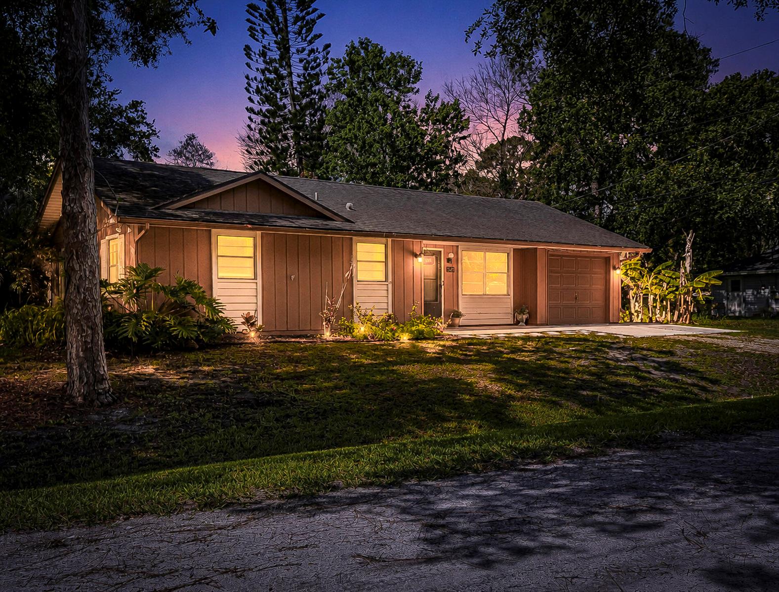 A single-story house with brown siding and an attached garage at dusk — 8745 24th Street, Vero Beach FL 32966, VERO BEACH, FL