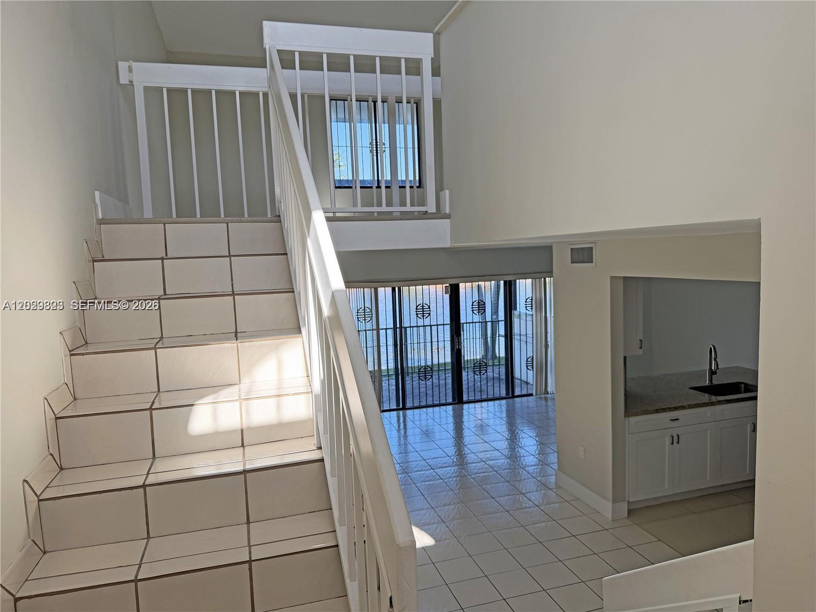 A staircase with light-colored tiles leads down to a living area with a kitchen — 1331 SW 124th Ct # 3, Miami FL 33184, MIAMI, FL