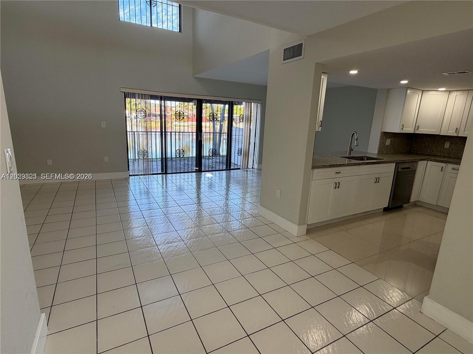 An open-concept living area features white tile flooring, a kitchen with white cabinets, and balcony doors — 1331 SW 124th Ct # 3, Miami FL 33184, MIAMI, FL