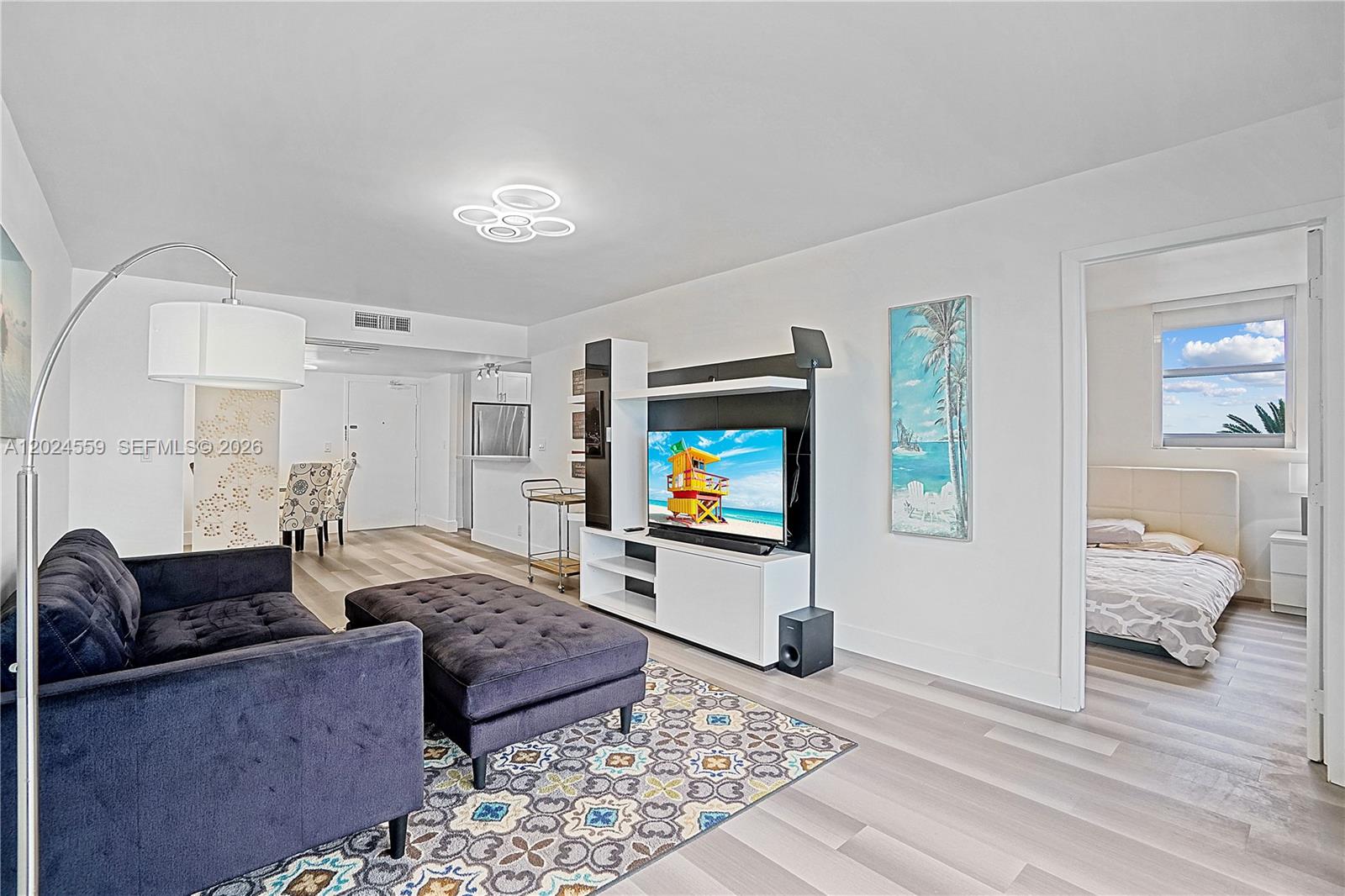 A living room features a dark sofa, a patterned rug, and an adjacent bedroom — 9273 Collins Ave # 309, Surfside FL 33154, SURFSIDE, FL