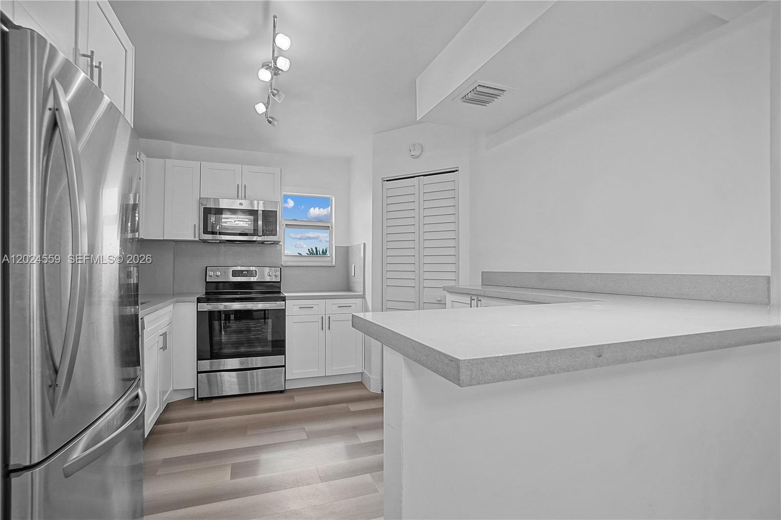A kitchen features white cabinetry, stainless steel appliances, and a light-colored countertop — 9273 Collins Ave # 309, Surfside FL 33154, SURFSIDE, FL