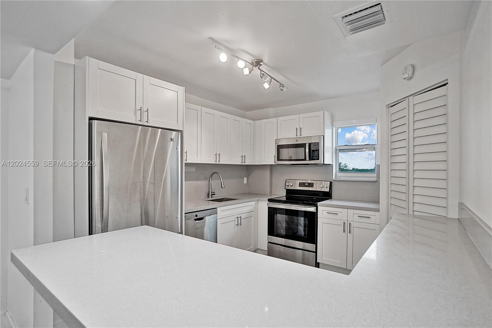 A modern kitchen features white cabinets, stainless steel appliances, and white quartz countertops — 9273 Collins Ave # 309, Surfside FL 33154, SURFSIDE, FL