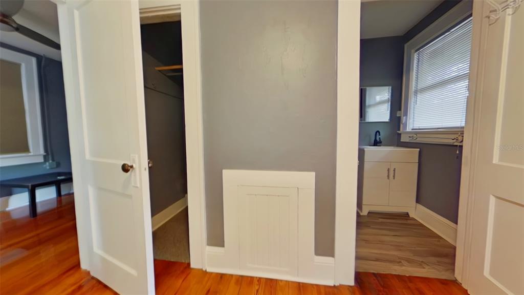 A hallway with hardwood floors leads to a closet and a bathroom with a vanity — 1412 NW 3RD AVENUE UNIT Upstairs, GAINESVILLE, FL