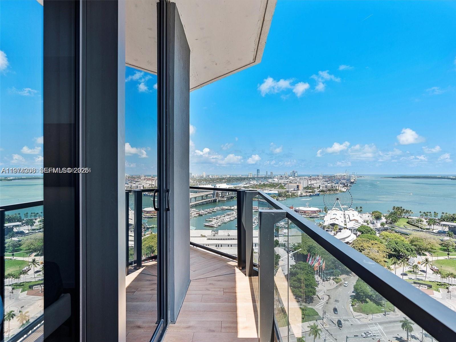 A high-rise balcony with wood-look tile flooring overlooks a marina, city skyline, and bay — 398 NE 5th St # 1915, Miami FL 33132, MIAMI, FL