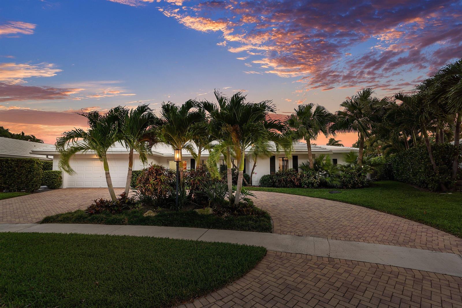 A single-story white house with a brick driveway and palm trees under a sunset sky — 800 Holly Lane, Boca Raton FL 33486, BOCA RATON, FL