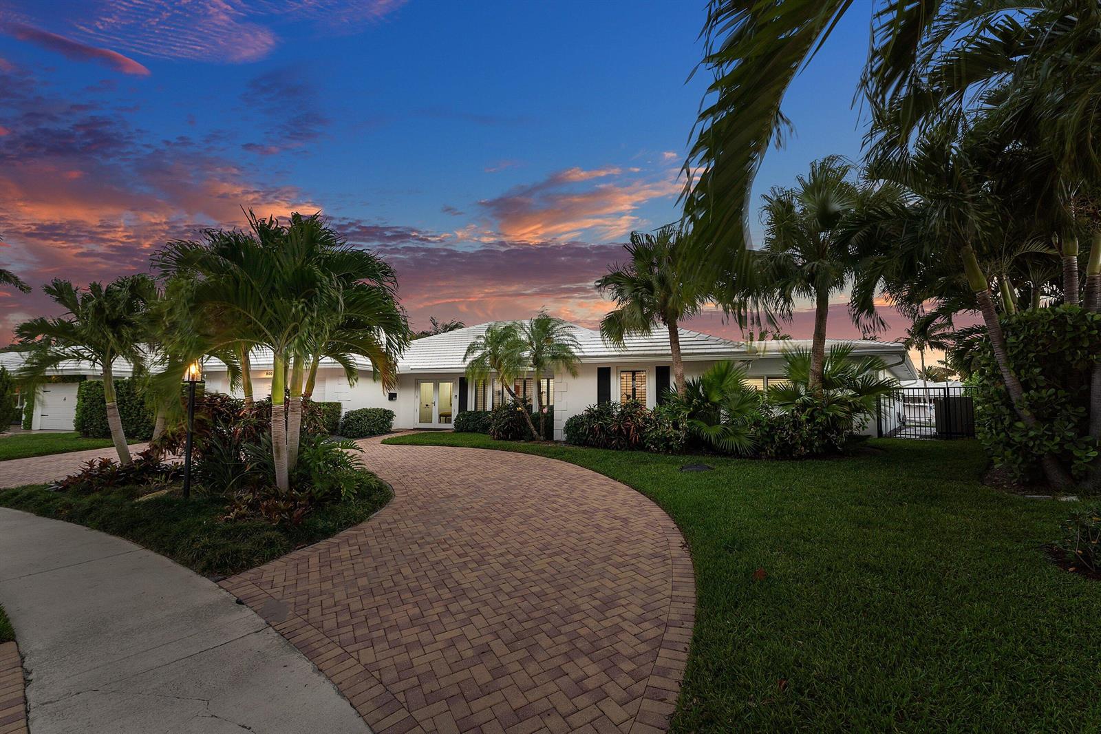 A white single-story house with a brick driveway and palm trees at sunset — 800 Holly Lane, Boca Raton FL 33486, BOCA RATON, FL