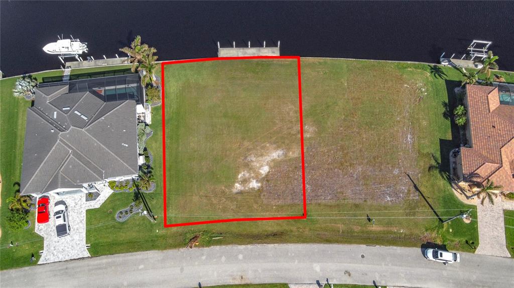 An aerial view shows a vacant waterfront lot outlined in red between two existing houses — 3338 SANDPIPER DRIVE, PUNTA GORDA, FL