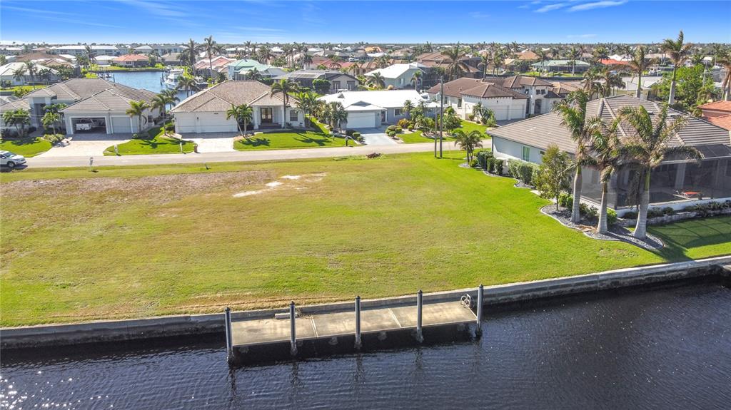 An aerial view of a vacant waterfront lot featuring a concrete dock and grassy yard — 3338 SANDPIPER DRIVE, PUNTA GORDA, FL