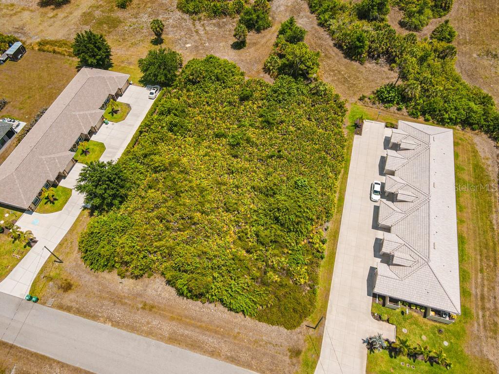 An aerial view shows a vacant, wooded lot situated between two residential buildings — 18 DONLON DRIVE, ROTONDA WEST, FL