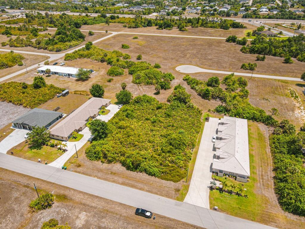 An aerial view shows a residential street with several houses and a vacant lot — 18 DONLON DRIVE, ROTONDA WEST, FL