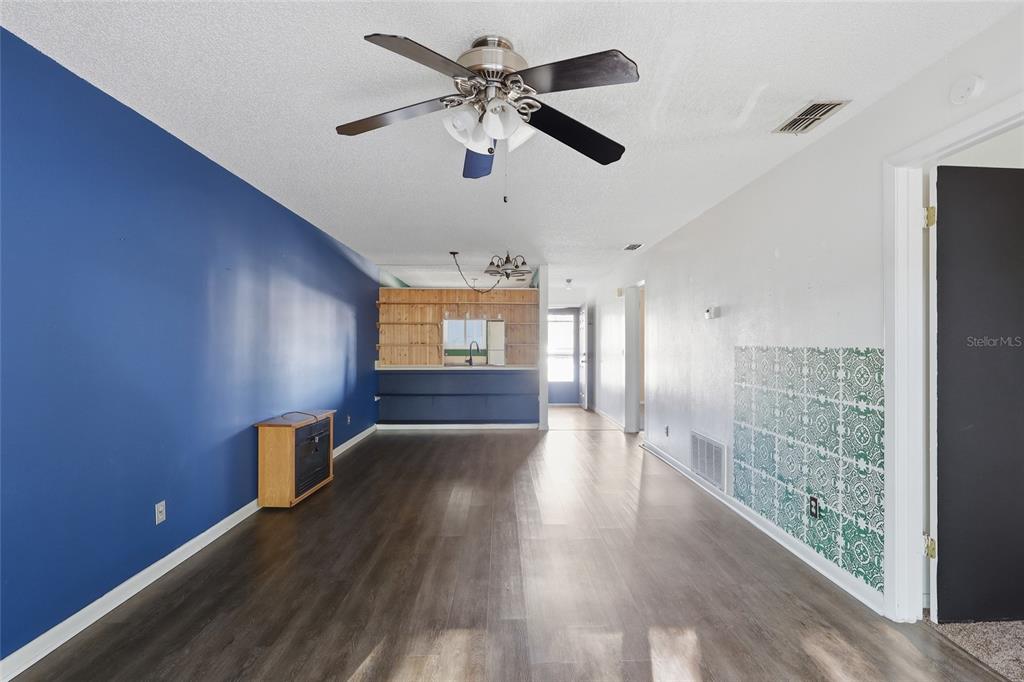 A living room features dark wood-look flooring, a blue accent wall, and a ceiling fan — 39132 COUNTY ROAD 54 UNIT 2216, ZEPHYRHILLS, FL