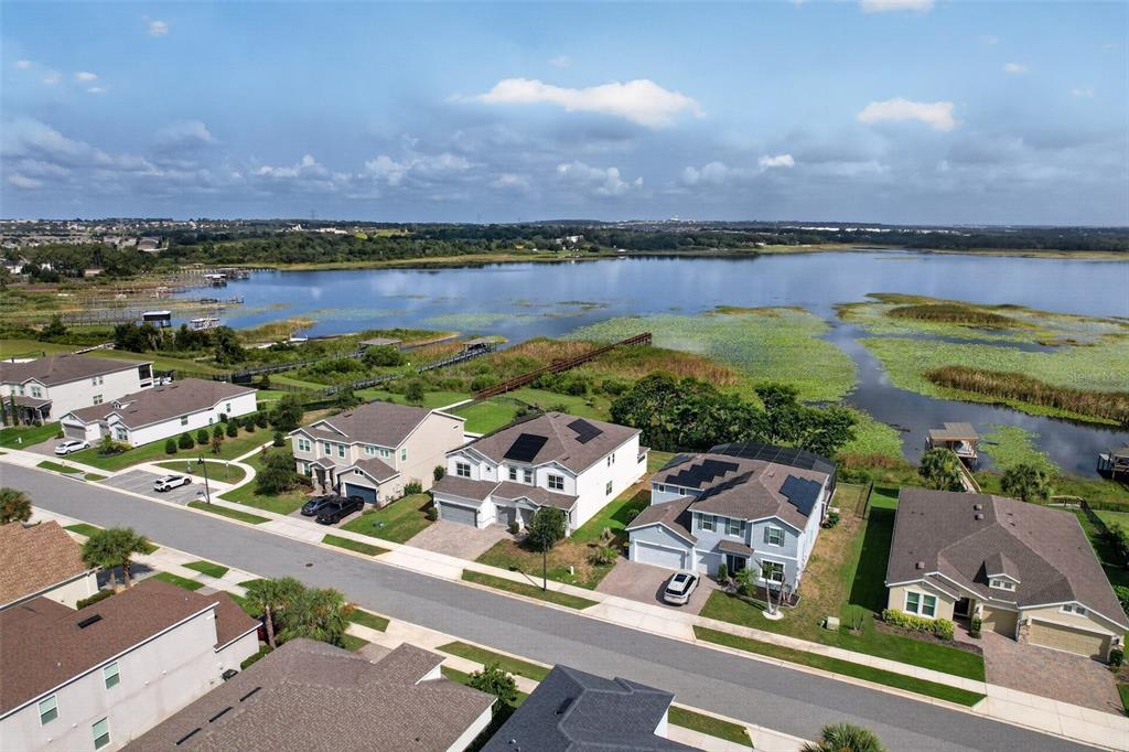 An aerial view shows suburban houses with solar panels near a lake and wetlands — 3399 BUOY CIRCLE, WINTER GARDEN, FL