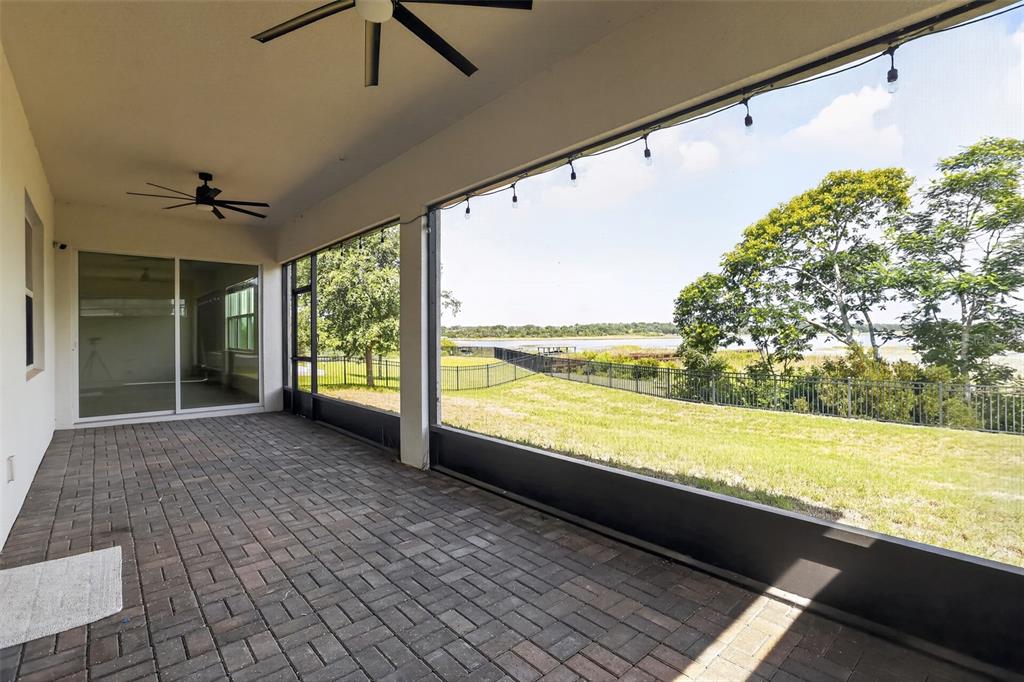 A covered patio with brick pavers, ceiling fans, and a screened view of a lake — 3399 BUOY CIRCLE, WINTER GARDEN, FL