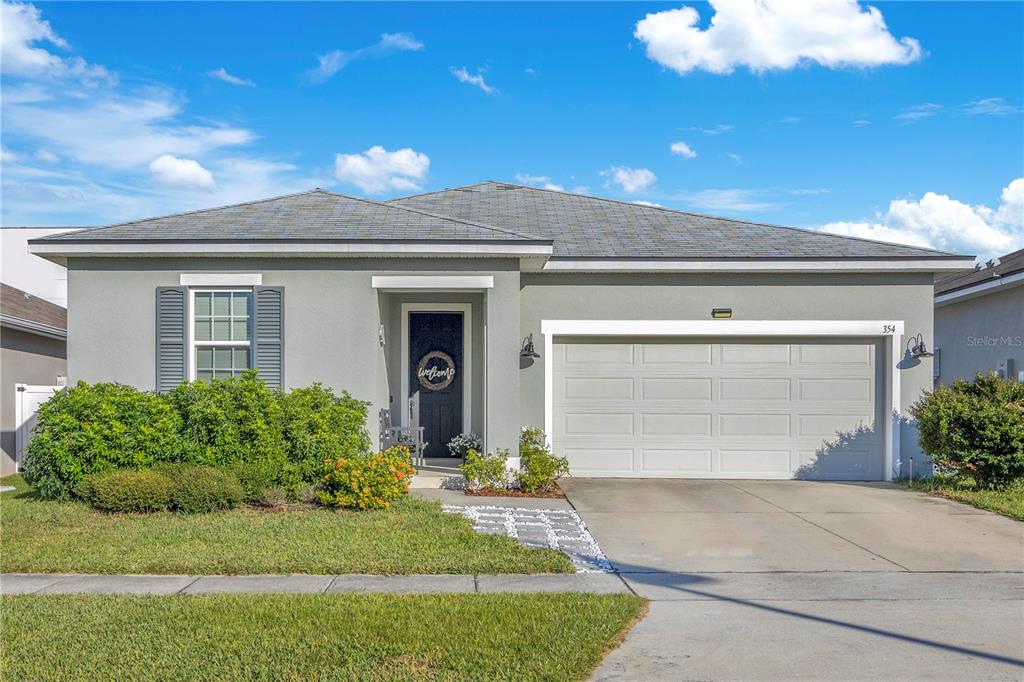 A single-story house with a gray stucco exterior, a two-car garage, and a front lawn — 354 CASA VERANO LANE, DAVENPORT, FL