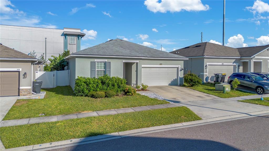 A single-story house with a light green exterior, a two-car garage, and a front lawn — 354 CASA VERANO LANE, DAVENPORT, FL