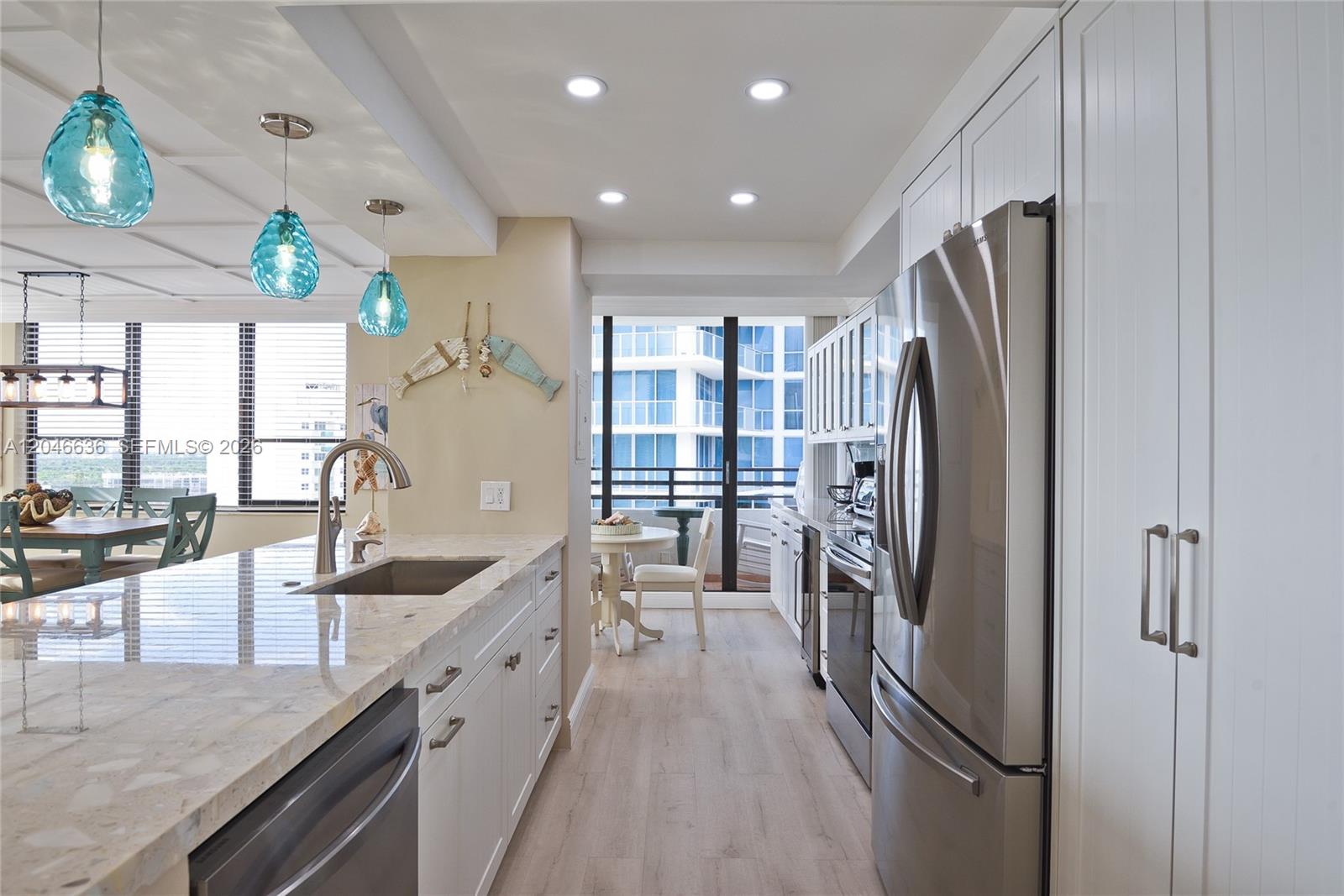 A modern kitchen features white cabinetry, stainless steel appliances, and a stone-topped island — 3505 S Ocean Dr # 1505, Hollywood FL 33019, HOLLYWOOD, FL
