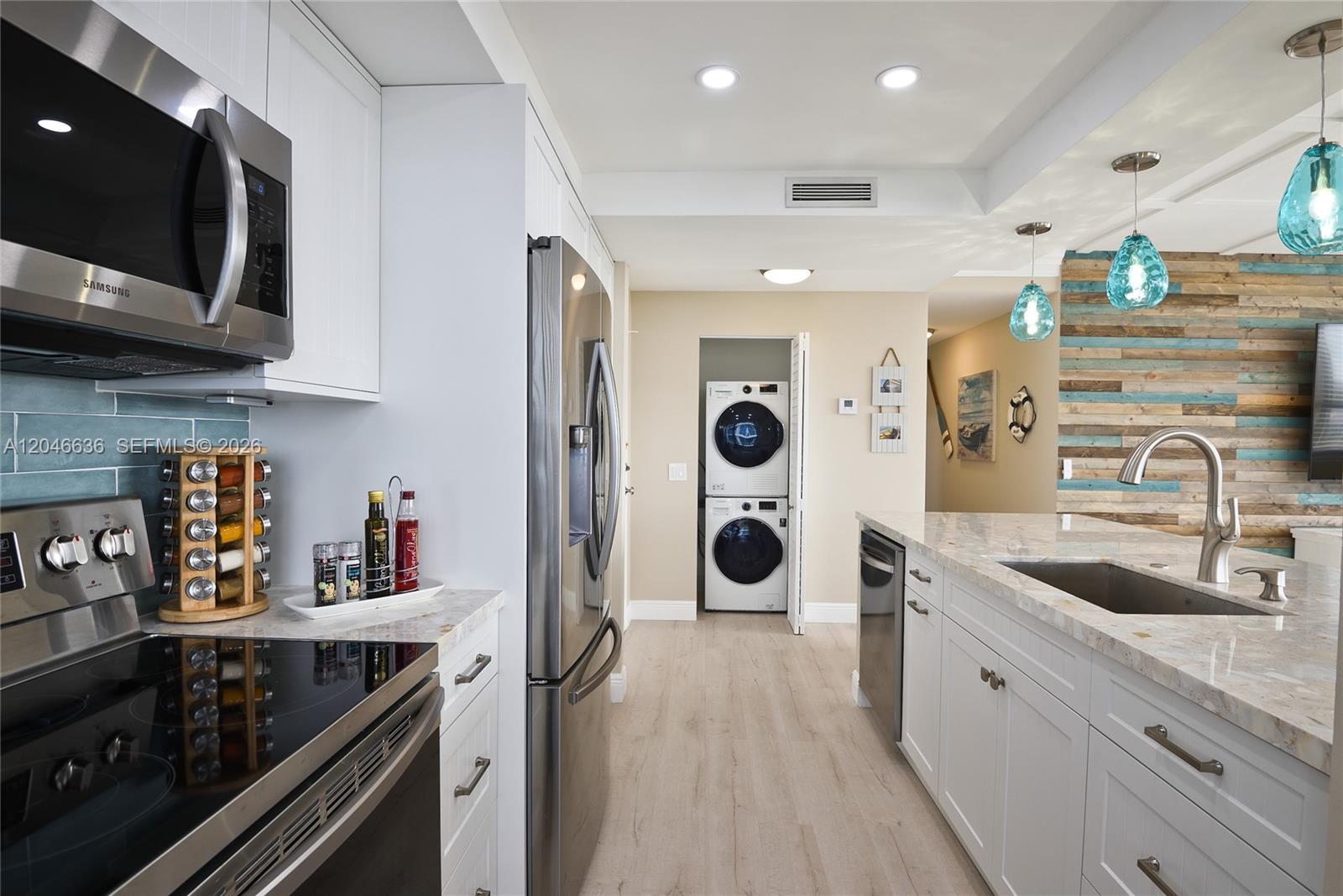 A kitchen features white cabinets, stainless steel appliances, a stone countertop, and a laundry closet — 3505 S Ocean Dr # 1505, Hollywood FL 33019, HOLLYWOOD, FL