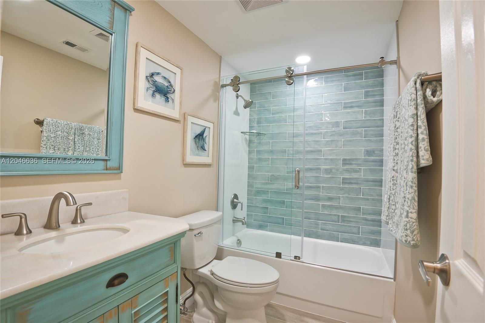A bathroom features a blue vanity, a glass-enclosed tub shower with blue tiles, and artwork — 3505 S Ocean Dr # 1505, Hollywood FL 33019, HOLLYWOOD, FL