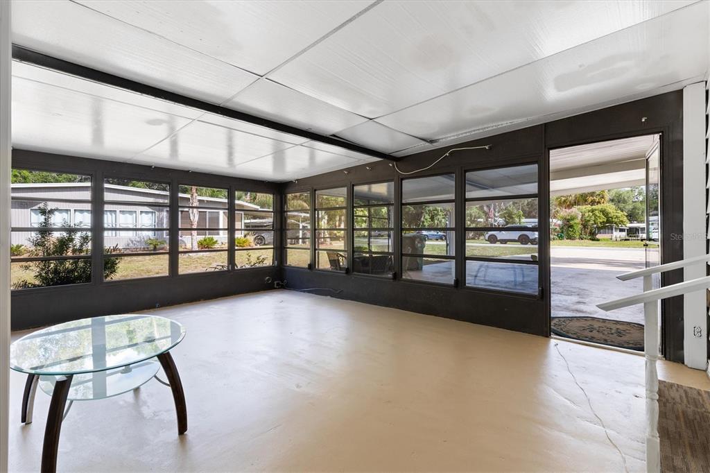 A sunroom with dark walls, large windows, a light floor, and a glass table — 5556 COLUMBUS CIRCLE, WILDWOOD, FL