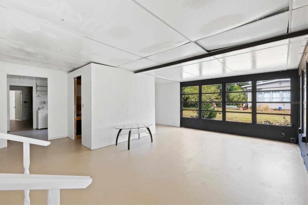 A sunroom with white walls, a light-colored floor, and large windows overlooking a grassy yard — 5556 COLUMBUS CIRCLE, WILDWOOD, FL
