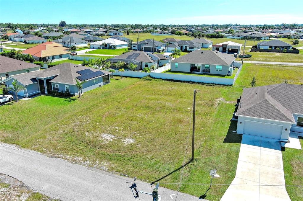 An aerial view shows a vacant residential lot situated between two single-family homes — 3548 NW 21ST TERRACE, CAPE CORAL, FL