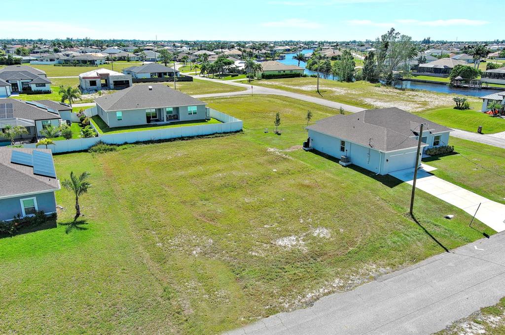 An aerial view shows a vacant residential lot situated between two single-family homes — 3548 NW 21ST TERRACE, CAPE CORAL, FL
