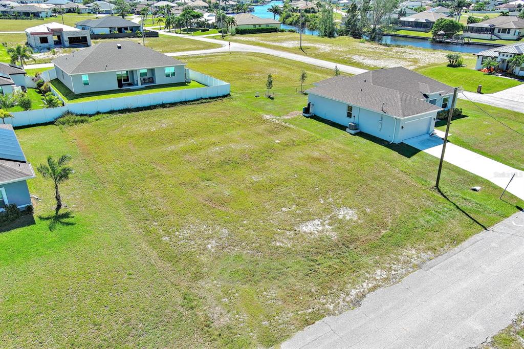 An aerial view shows a vacant residential lot situated between two single-family homes — 3548 NW 21ST TERRACE, CAPE CORAL, FL