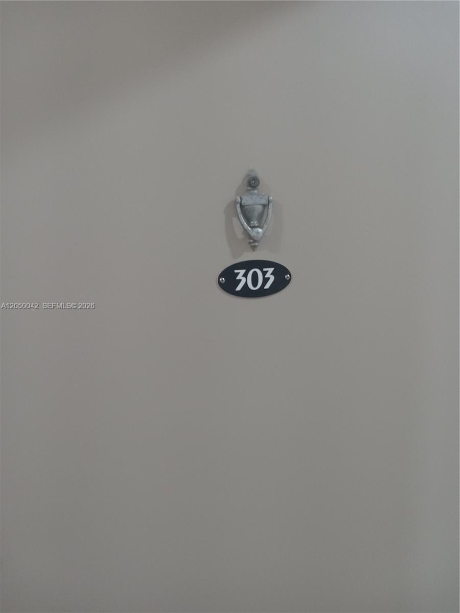 A silver door knocker is mounted above a black oval sign displaying the number 303 — 8315 SW 72nd Ave # 303B, Miami FL 33143, MIAMI, FL