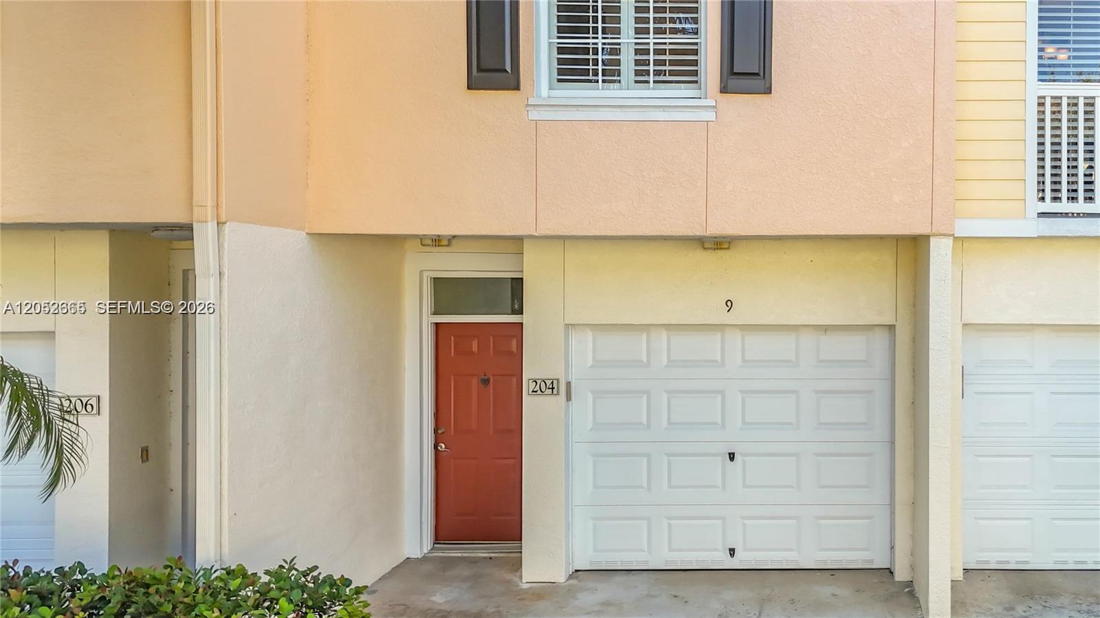 The exterior view shows a townhouse with a red front door and a white garage — 125 Galicia Way # 204, Jupiter FL 33458, JUPITER, FL