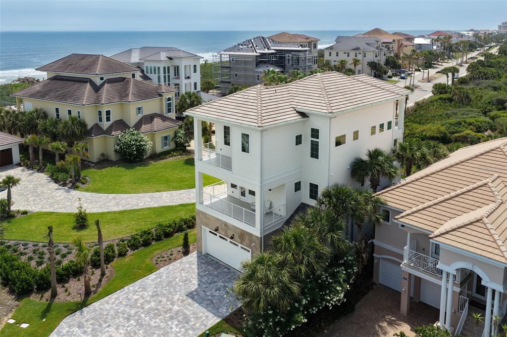 An aerial view shows a multi-story white house with balconies and a paved driveway — 546 CINNAMON BEACH LANE, PALM COAST, FL