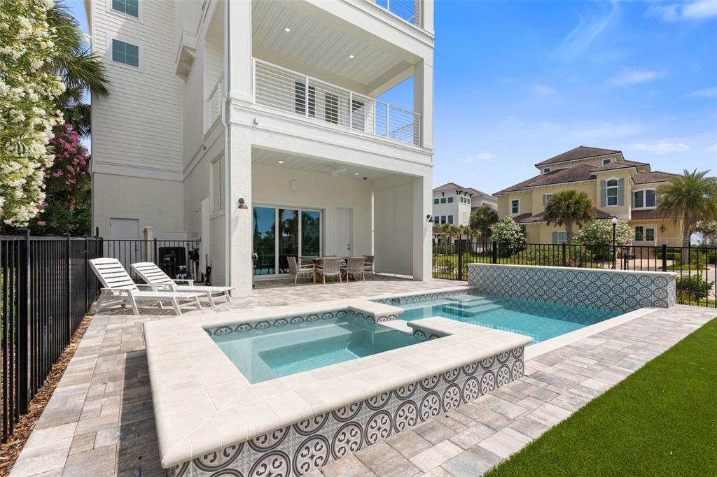 A backyard patio features a swimming pool, a hot tub, and lounge chairs — 546 CINNAMON BEACH LANE, PALM COAST, FL